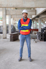 vertical image of attractive young male engineer wearing safety gear,standing arms crossed,smiling...