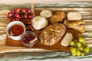 Overhead view of bread and cheese board on decorated table with fruits and sauces