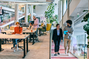 In a modern startup office, a diverse group of young professionals collaboratively tackles various...