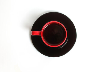 The Red Cup with Tea on the Black Plate on a White Background Top View