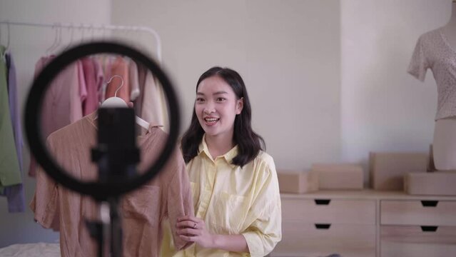 Beautiful Asian woman holding tablet and show code for discount code coupon video call for sell clothes live stream selling online, marketing delivery SME e-commerce 