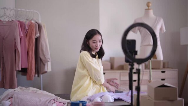 Beautiful Asian woman holding tablet and show code for discount code coupon video call for sell clothes live stream selling online, marketing delivery SME e-commerce 