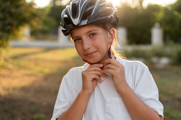 Cyclist teenager putting bike helmet on for head protection on outdoor sport activity or commute...