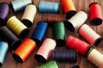 Scattered spools of thread on a seamstress's wooden table. Embroidery theme.