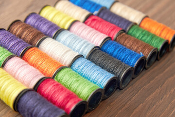 Set of colorful thread spools on the wooden seamstress's table. Sewing background with copy space