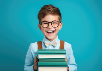 Portrait of cute little boy with books on color background