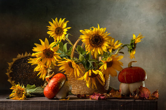 Still life with a bouquet of sunflowers and decorative pumpkins on an old wooden table