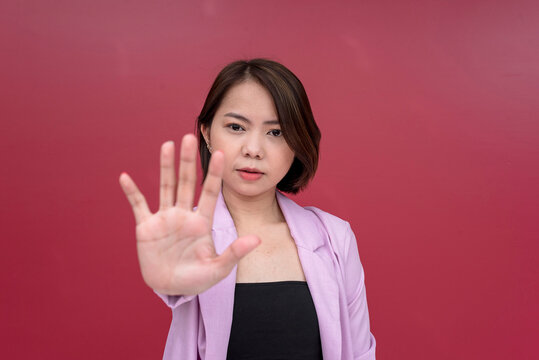 A stern young asian woman . Studio shot with burgundy background.