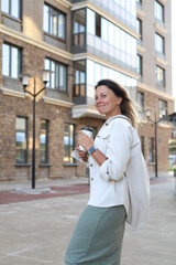 woman holding a glass of coffee in her hands, walking around the city at lunchtime