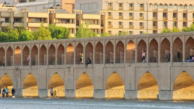 Isfahan, Iran - May 2022: people walk around SioSe Pol or Bridge of 33 arches, one of the oldest bridges of Esfahan and longest bridge on Zayandeh River