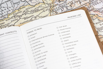 Close-up of a travel journal's packing list page against a vintage map background.