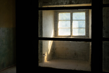 Sunlight entering a dark spooky room through filthy windows in an abandoned house