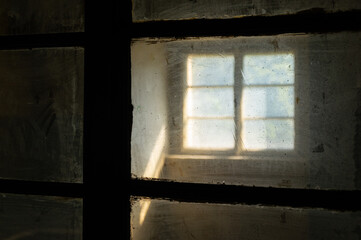Sunlight entering a dark spooky room through filthy windows in an abandoned house