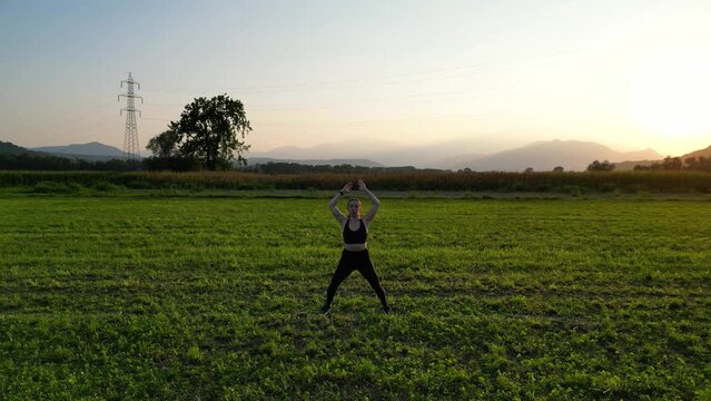 Woman Doing some Jumping Jacks at Sunset in the Countryside, Aerial View