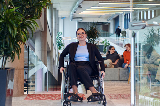 In a modern office, a young businesswoman in a wheelchair is surrounded by her supportive colleagues, embodying the spirit of inclusivity and diversity in the workplace