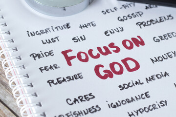 Focus on God, handwritten words in notebook with magnifying glass. Close-up. Christian faith,...