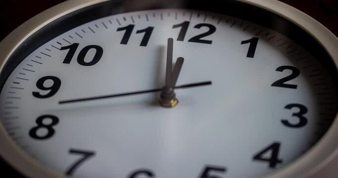 Time lapse of a white frame wall clock. Focus change from blur to sharp, while the time running. Stop watch. Close-up of the white clock face in timelapse during the day. Counting down the hours
