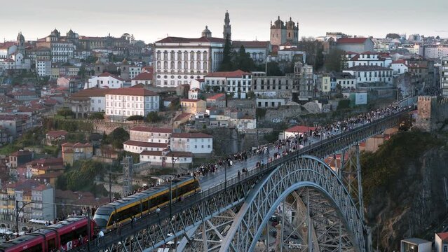 Establishing shot of Porto cityscape showing train crossing the Dom Luis I Bridge over the Douro River at sunset in Porto (Oporto), Portugal.