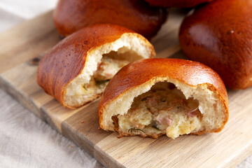 Homemade Pirozhki with Potato and Bacon on a wooden board, side view.