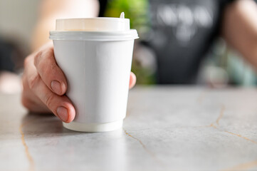 Barista hold a takeaway coffee in a paper cup