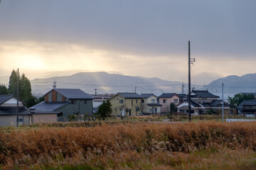 Fototapeta na wymiar Basking in the radiant glow of the golden sunlight, a picturesque scene unfolds in the Japanese rural landscape. A row of traditional houses stands gracefully amidst the serene countryside,