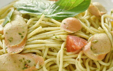 pesto spicy stir fried spaghetti with slice sausage and basil sauce on plate 