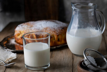 Milk in a glass and decanter on a wooden table