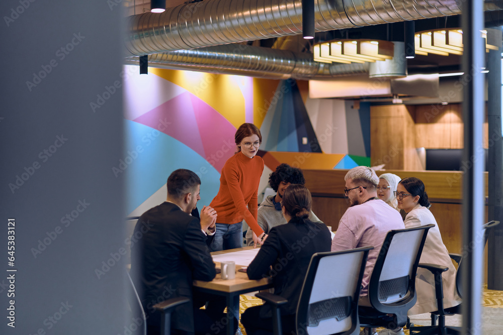 Wall mural a diverse team of business experts in a modern glass office, attentively listening to a colleague's 