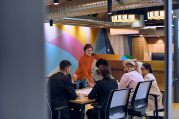 A diverse team of business experts in a modern glass office, attentively listening to a colleague's presentation, fostering collaboration and innovation.