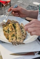 woman with a fork in a river eats fish