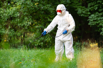 A worker sprays pesticides in an open park on the lawn. Pest control