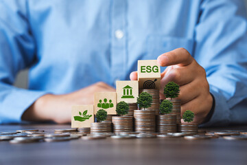ESG Concepts in Environment, Society and Governance Invest in green finance Sustainable organizational development Businessman holding a flipping wooden block On the coin a tree grows. - obrazy, fototapety, plakaty