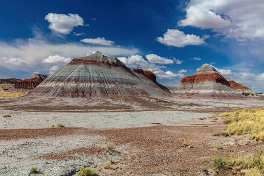 "Teepee" hills in the Petrified Forest National Park, Arizona. The formations show layered bands of multi-colored sediment. Blue sky and clouds above. 
