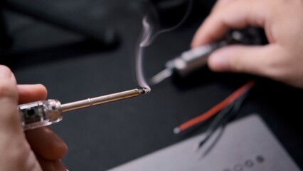Close-up shot of a man's hands working with a soldering iron. The engineer work.