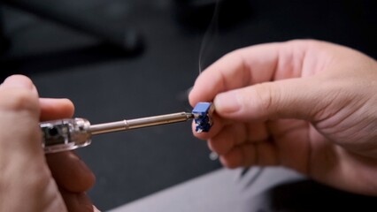 An engineer connects two parts of a radio circuit with a soldering iron.