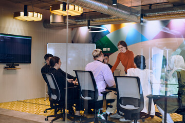 Fototapeta na wymiar A diverse team of business experts in a modern glass office, attentively listening to a colleague's presentation, fostering collaboration and innovation.