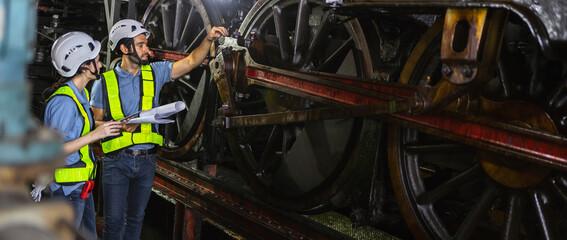 Female engineer and worker checking equipment in factory for repair