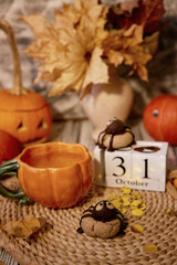 Autumn Halloween background - cookies in shape of spider and cup of tea among pumpkins and Jack o lantern. 31 of October on calendar.