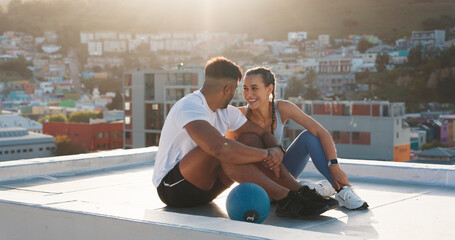 Fitness, rest and happy couple outdoor for exercise, workout or training together on a city building rooftop. Man and woman on urban break with medicine ball, conversation or health and wellness