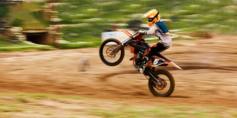 Motorcycle, balance and motion blur with a man at a race on space in the forest for dirt biking. Bike, fitness and power with a sports person driving fast on an off road course for freedom or speed