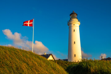 Iconic lighthouse of Hirsthals,  Jutland, Denmark. The setting is extraordinary, surrounded by cliffs, dunes, sandy beaches and historical WWII bunkers - obrazy, fototapety, plakaty