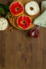 Set of fresh bread bagels with jam on wooden board, top view