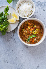Red curry chicken with white rice in bowl on grey background
