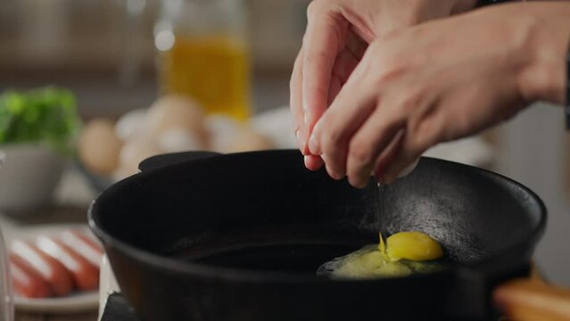 Fry. Happy young parent girl in a kitchen apron breaks an egg into a frying pan in the kitchen. Camera movement modern girl beats egg shells on a frying pan maintaining a balanced diet, bread