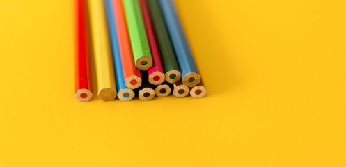 Lots of colored pencils on the yellow background of the desk. Back to school. Children's Creativity and Education