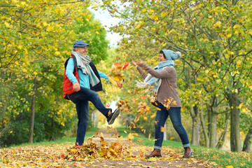 ausgelassenes Paar im Herbst wirft mit Laub