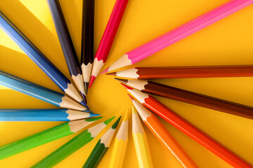 Lots of colored pencils on the yellow background of the desk. Back to school. Children's Creativity and Education