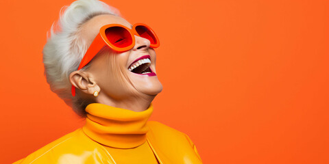 a beautiful old woman laughing on a plain orange background, fashion - obrazy, fototapety, plakaty