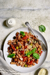 Pasta alla norma, fusilli with eggplants, tomatoes and olives. Traditional dish of sicilian cuisine. Top view with copy space.