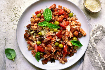 Pasta alla norma, fusilli with eggplants, tomatoes and olives. Traditional dish of sicilian cuisine. Top view with copy space.